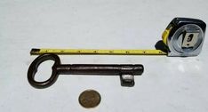 an old key with a measuring tape and a penny