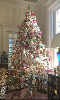 a white christmas tree in a living room with lots of ornaments on the top and bottom