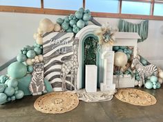 an entrance to a party decorated with balloons and streamers in mint green, white and gold colors