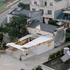 an aerial view of a building with two people walking around it and some buildings in the background