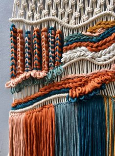 an assortment of different colored yarns hanging on a wall