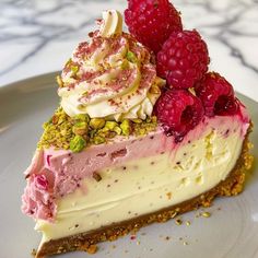 a piece of cheesecake with raspberries and pistachios on top