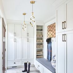 a walk in closet filled with lots of white cupboards and hanging lights above it