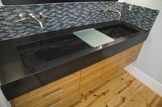 two black sinks in a bathroom with wood flooring and mosaic tile backsplash