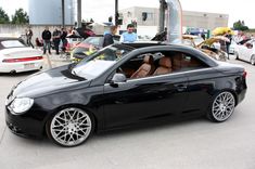 a black car parked in front of a building with lots of other cars behind it