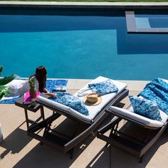 a woman laying on top of a chaise lounge next to a blue swimming pool