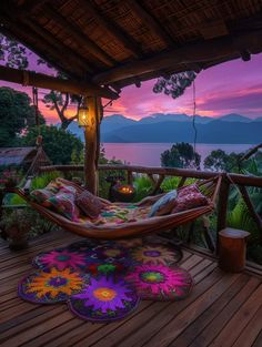 a hammock on a deck with a view of the ocean and mountains at sunset