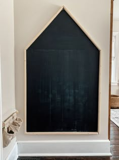 a blackboard in the corner of a room with wood flooring and white walls