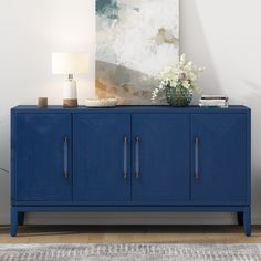 a blue sideboard with two doors and a vase on top in a living room