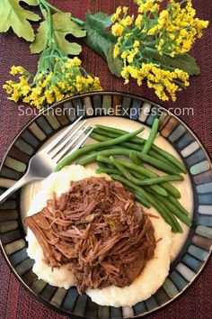 a plate with green beans, mashed potatoes and shredded beef on it next to yellow flowers