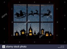 silhouettes of santa sleigh and reindeer on the window sill at night - stock image