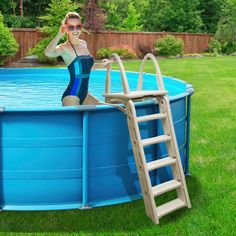 a woman in a blue swimsuit standing next to a ladder leaning on a pool