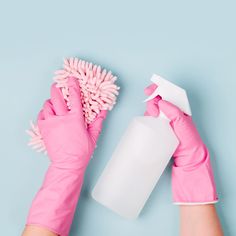 a person in pink gloves holding a spray bottle and a cleaning brush on a blue background