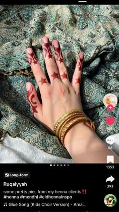 someones hand with red and white paint on it, laying down next to a blanket