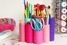 several pens, scissors and other crafting supplies are in a holder on a table