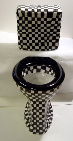 a black and white checkered toilet sitting on top of a white floor next to a bag