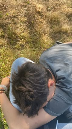 a boy laying on the ground with his head in his hands and looking down at something