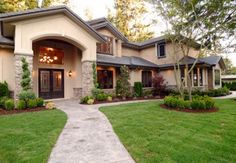 a house with lots of green grass and trees in front of the entrance to it