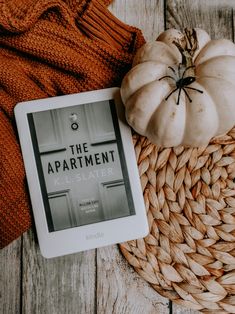 an ipad sitting on top of a wicker basket next to a white and orange pumpkin