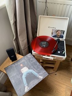 a record player sitting on top of a wooden table next to a red vinyl record