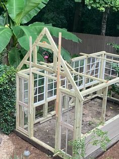 a small wooden greenhouse in the middle of a garden