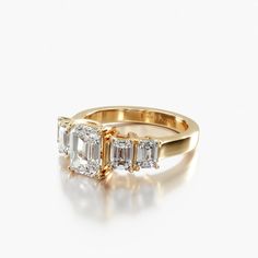 three stone diamond ring in yellow gold with diamonds on the sides and an emerald band