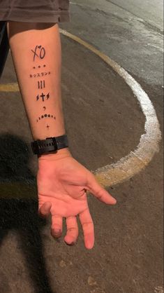 a person with a wrist tattoo holding their hand out to the side, while standing in front of a parking lot