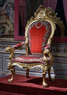 an ornate gold and red chair sitting in front of a window