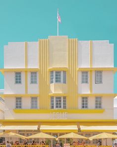 people are sitting at tables in front of a yellow and white building