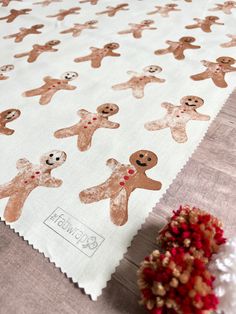 a white table cloth with brown and red gingerbreads printed on it, next to a potted plant