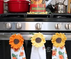 three sunflowers are hanging from the handles of an oven