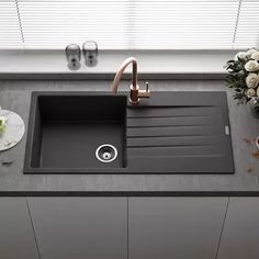 a kitchen sink sitting on top of a counter next to a vase with flowers in it