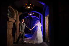 a bride and groom holding hands in an archway