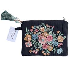 a black embroidered pouch with flowers and tassels on the front, sitting on a white background