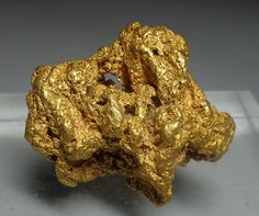 a gold nugget is shown on a white surface with some gray squares in the background