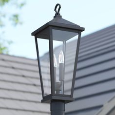 two lights are attached to the side of a lamp post in front of a house