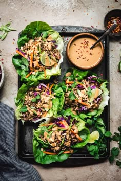 lettuce wraps filled with meat and vegetables on a tray next to dipping sauce