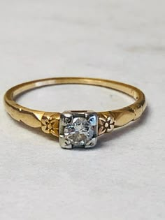 a gold ring with an old cut diamond in the center, on a white surface