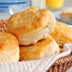 three biscuits stacked on top of each other in a basket next to a glass of orange juice