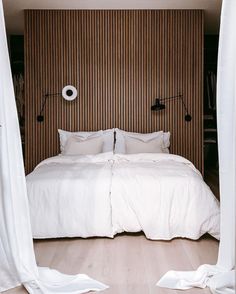 an instagram photo of a bed with white sheets, pillows and throw pillows on it