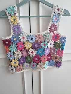 a crocheted top hanging on a door with flowers in the front and back