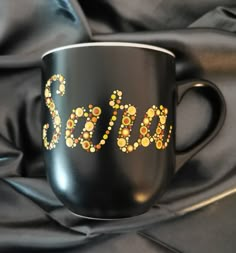 a black coffee cup with gold dots and the word sasa painted on it's side