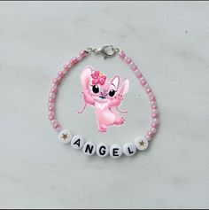 a pink beaded bracelet with an angel charm and name written on the front in white letters