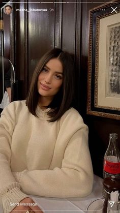 a woman sitting at a table in front of a framed photo and bottle of booze