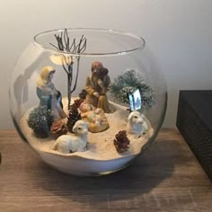 a glass bowl filled with small figurines sitting on top of a wooden table