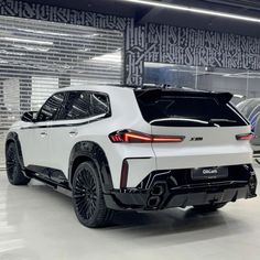 the rear end of a white suv parked in a garage