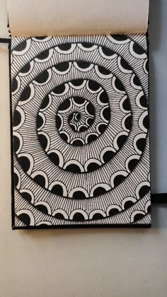 an intricate black and white artwork on a piece of paper that is hanging from a wall