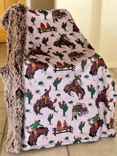 a chair covered in a blanket with horses and cactus print on the back, sitting on a tile floor