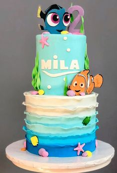 a blue and white cake with an image of finding nemo on the top tier