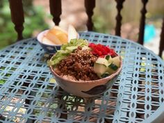 a bowl filled with food sitting on top of a blue table next to an apple